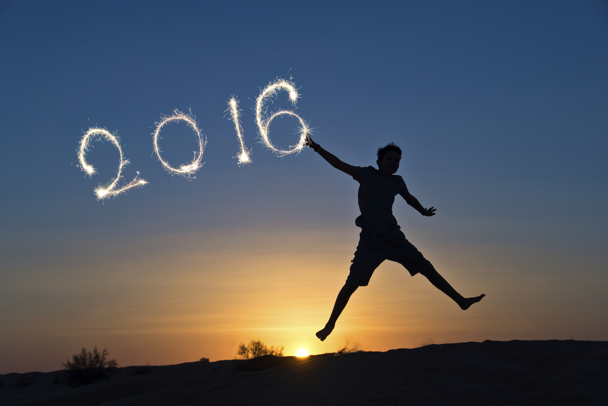 2016 written with sparkles, silhouette of a boy jumping in the sun