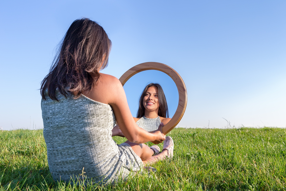 Woman,Sitting,On,Grass,Looking,At,Her,Mirror,Image