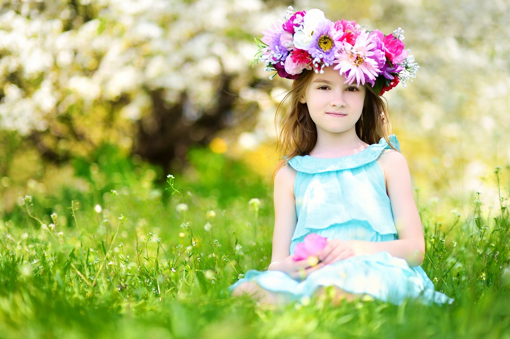 Adorable little girl in blooming cherry garden