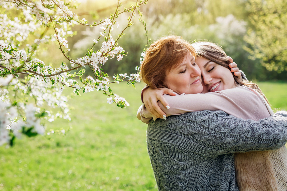 Middle-aged,Mother,And,Her,Daughter,Hugging,In,Blooming,Spring,Garden.
