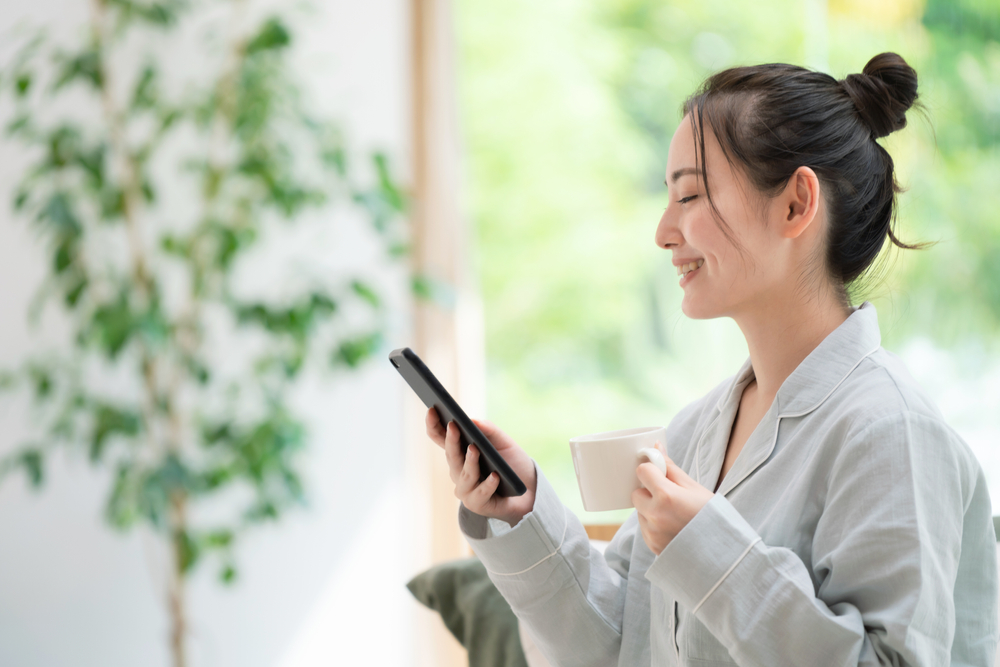 Young,Asian,Woman,Using,A,Smart,Phone,In,Bedroom.