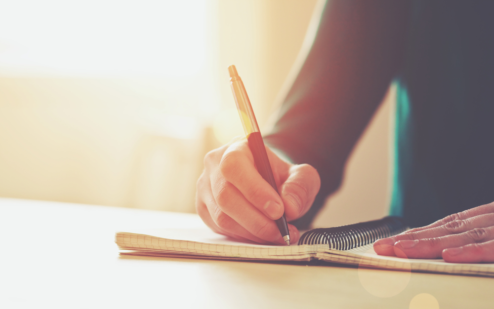 Female,Hands,With,Pen,Writing,On,Notebook